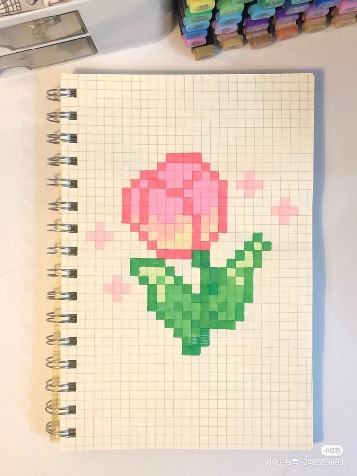 a notebook with a flower drawn on it next to some markers and crayons