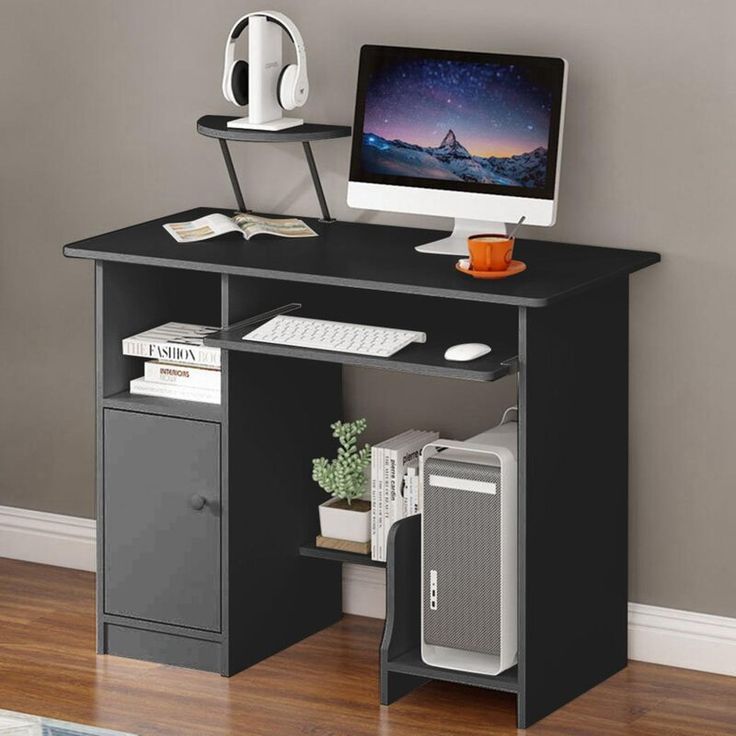 a computer desk with a monitor, keyboard and mouse on it in front of a gray wall