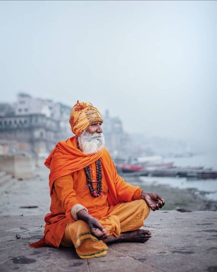 an old man sitting on the ground with his eyes closed and hands clasped in front of him