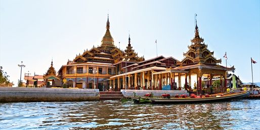 a long boat floating on top of a river next to tall buildings with spires