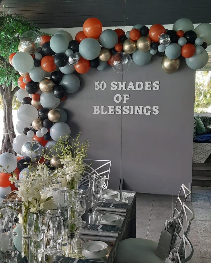 the table is set with silver, orange and black balloons that spell out 50 shades of blessinges