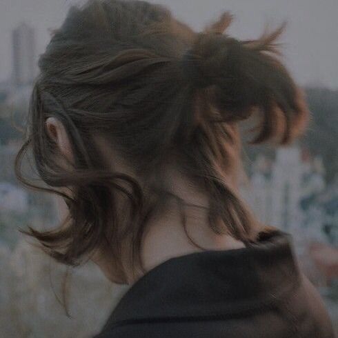 a woman with her hair pulled back in a ponytail looking out over the city skyline