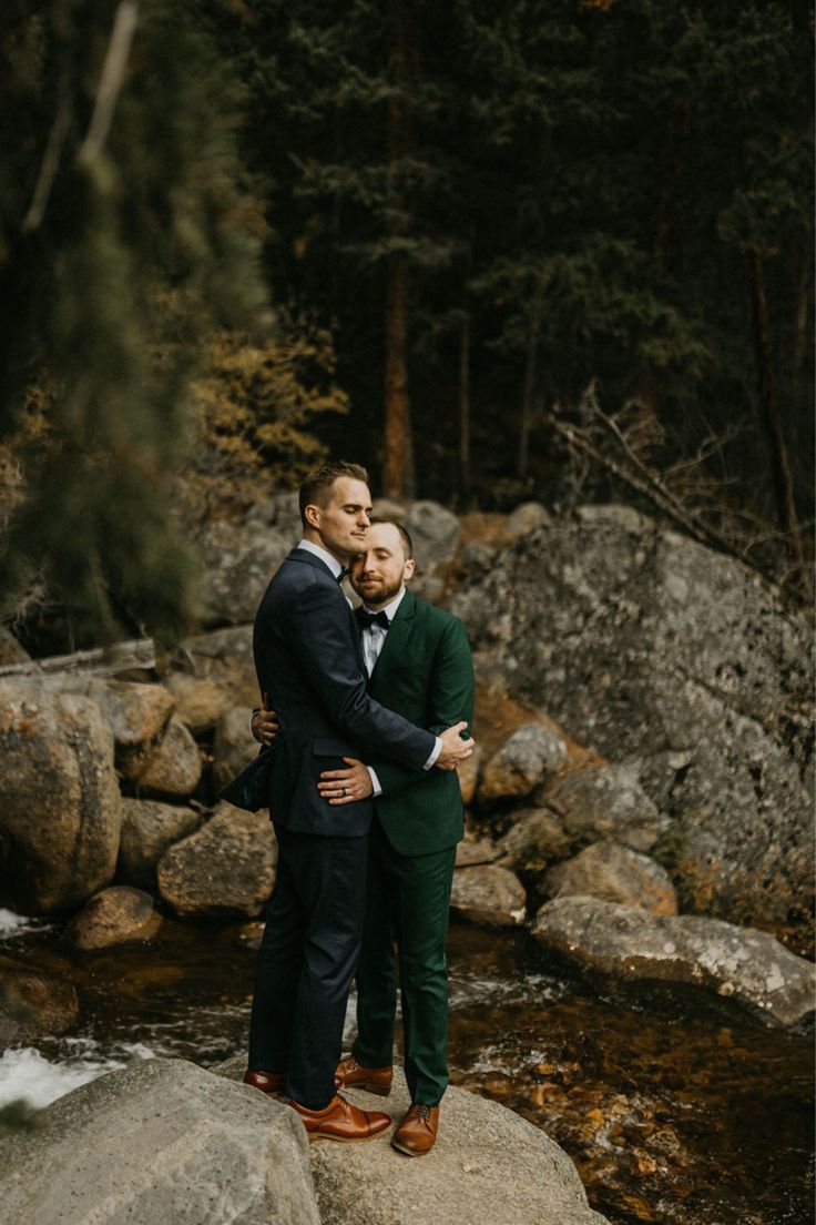 two men hugging each other while standing on rocks