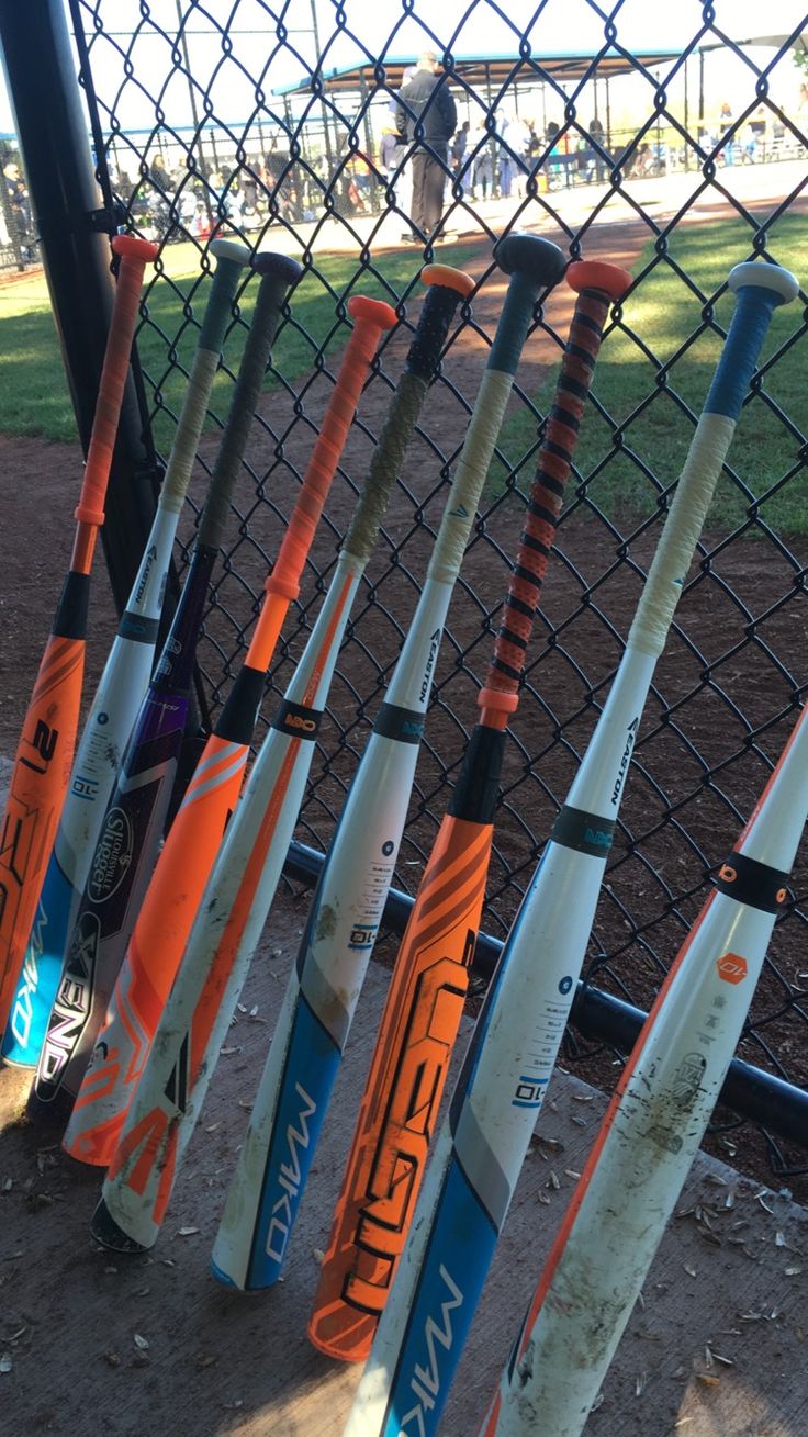 many baseball bats lined up against a fence