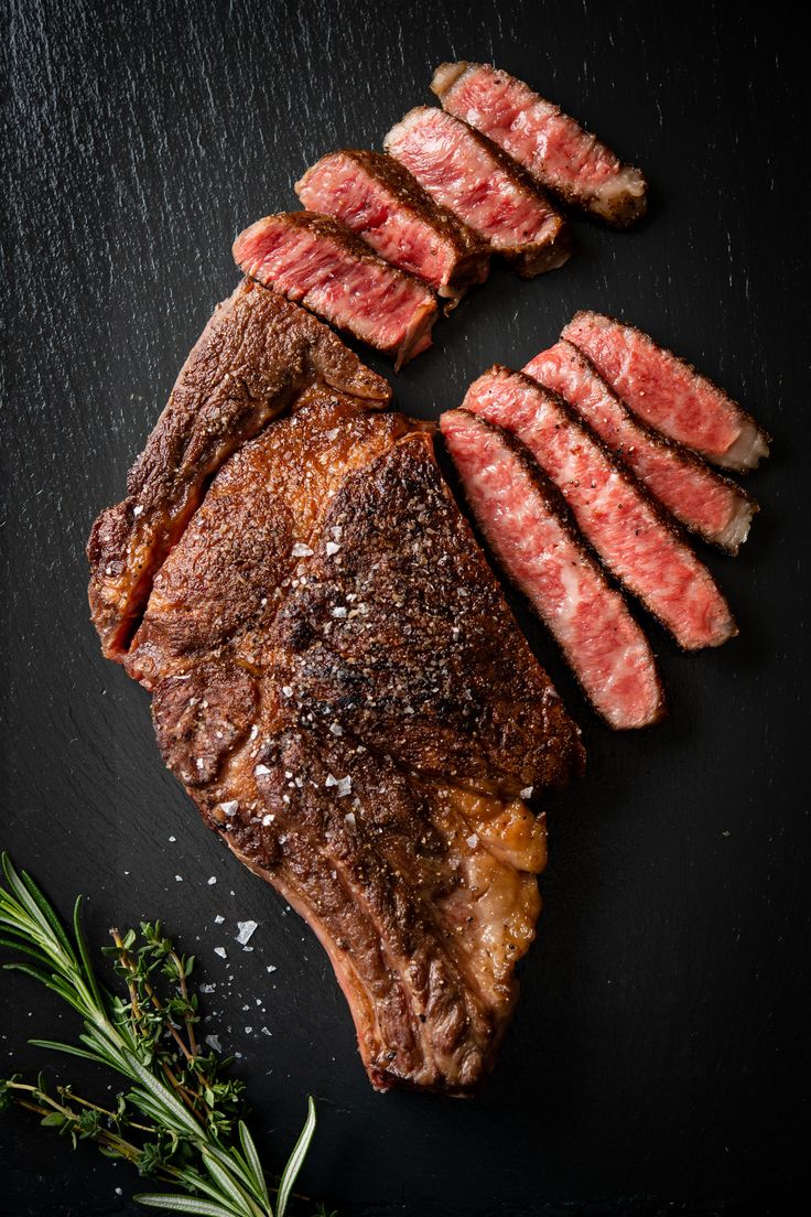 the steak has been sliced and is ready to be served on the table with herbs