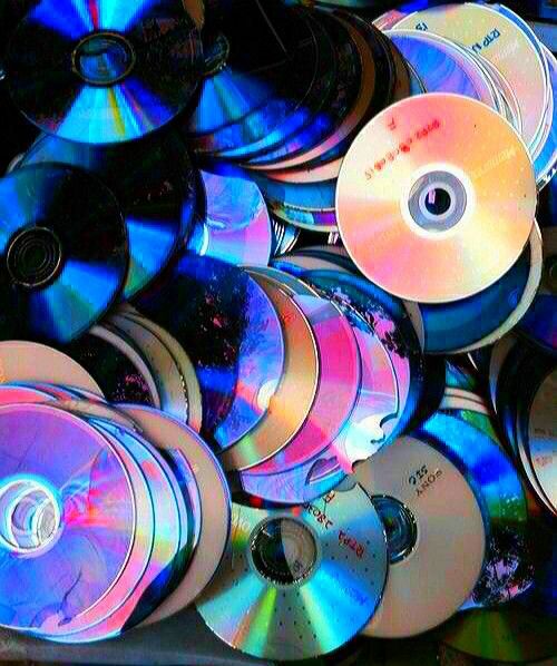 many cd's are stacked on top of each other in different colors and sizes