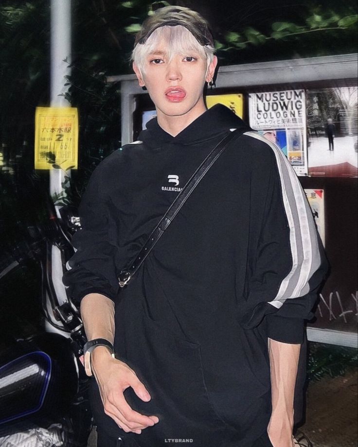 a young man with white hair wearing a black hoodie and carrying a handbag