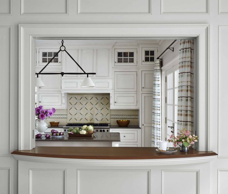 a kitchen with white cabinets and wooden counter tops, along with flowers in vases on the bar