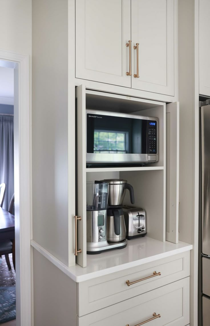 a kitchen with white cupboards and appliances in the corner next to a dining room table