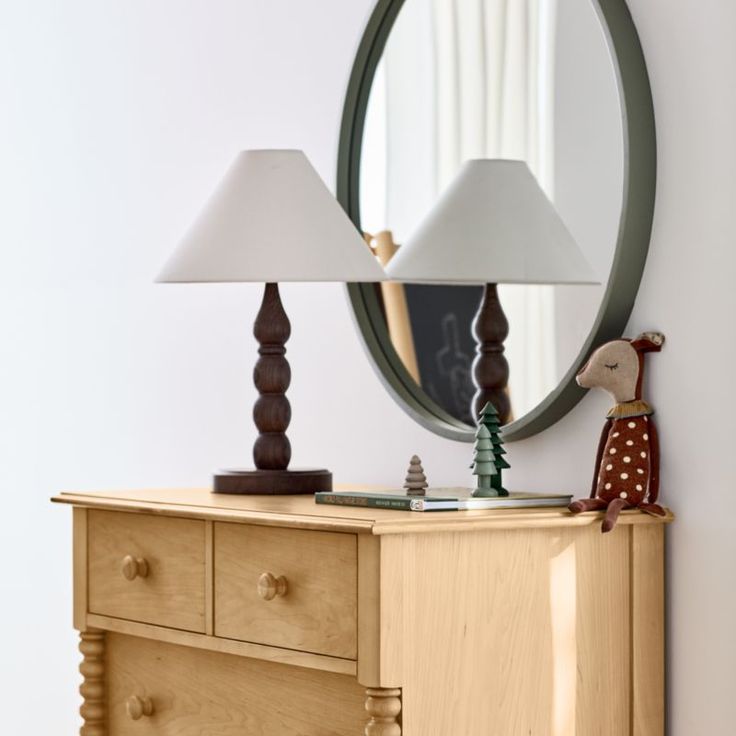 a wooden dresser with two lamps on top of it