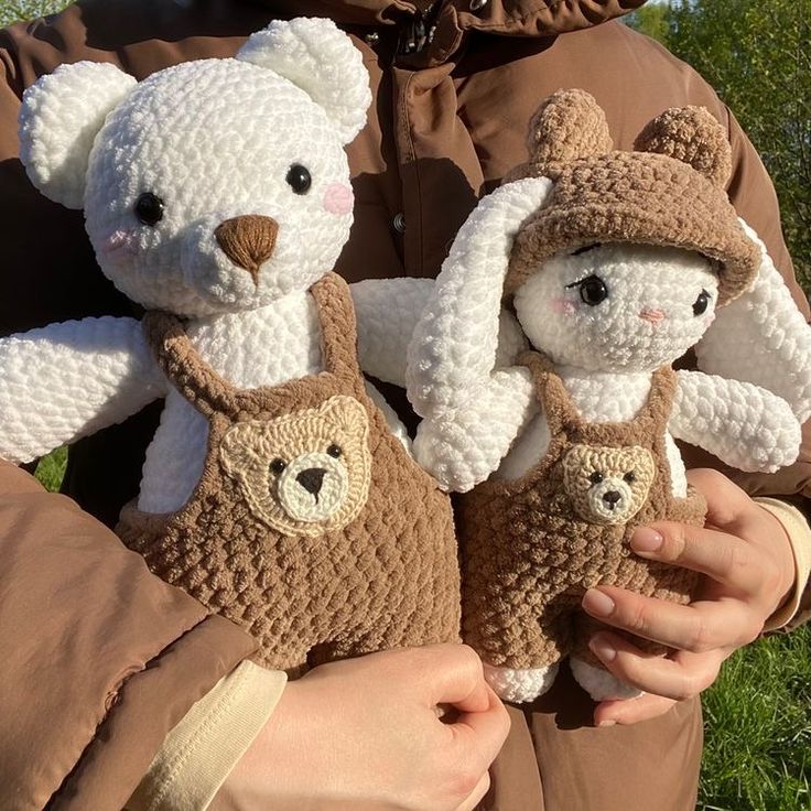 two crocheted teddy bears are being held in someone's hands while wearing brown clothing