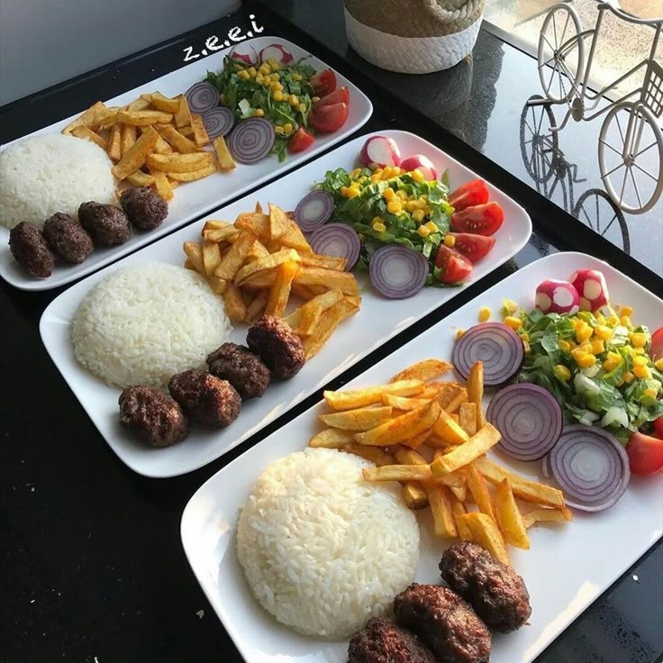 three plates filled with food sitting on top of a table next to salad and fries