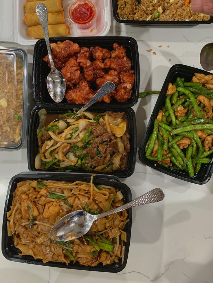 four plastic containers filled with different types of food and spoons on top of a table