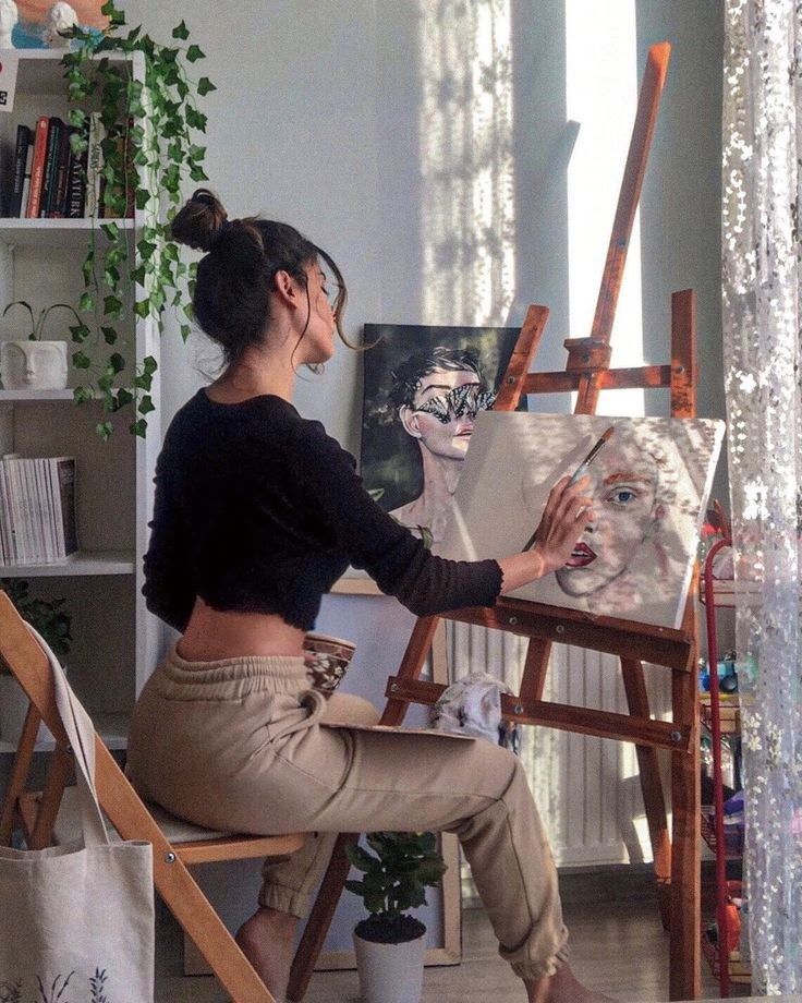 a woman sitting in front of an easel painting