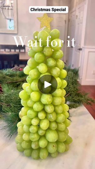 a christmas tree made out of grapes sitting on top of a kitchen counter with the words wait for it