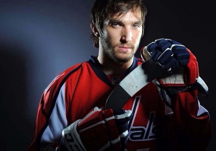 a man holding a hockey glove in his hands and looking at the camera with an intense look on his face