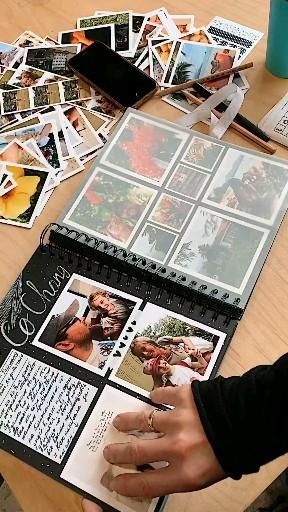 a table with many different pictures on it and someone's hand holding an open book