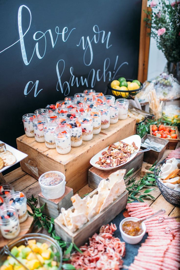 a table filled with lots of food on top of a wooden tray next to a chalkboard