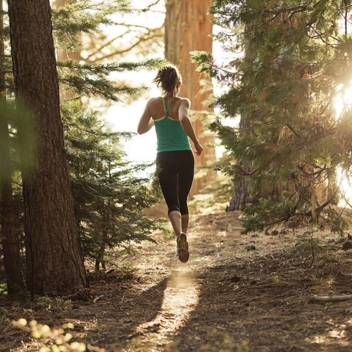 a woman running in the woods on a sunny day