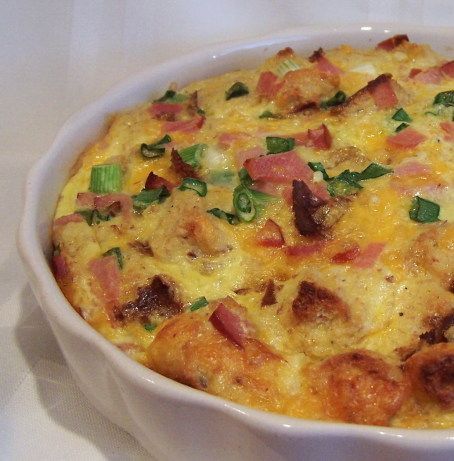 a casserole dish with ham, cheese and green onions in a white bowl