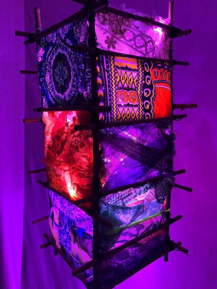 a multi - colored lamp hanging from the ceiling in front of a purple background with lights