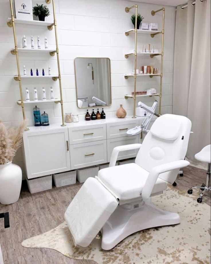 a white chair sitting in front of a mirror next to a shelf filled with bottles