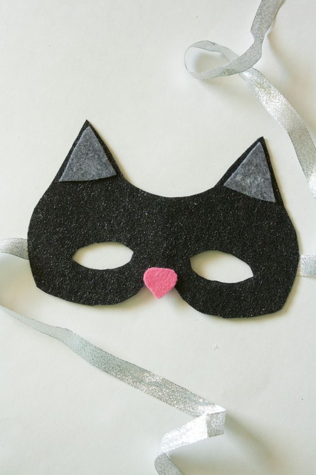 a black cat mask with a pink heart on it's nose and silver ribbon