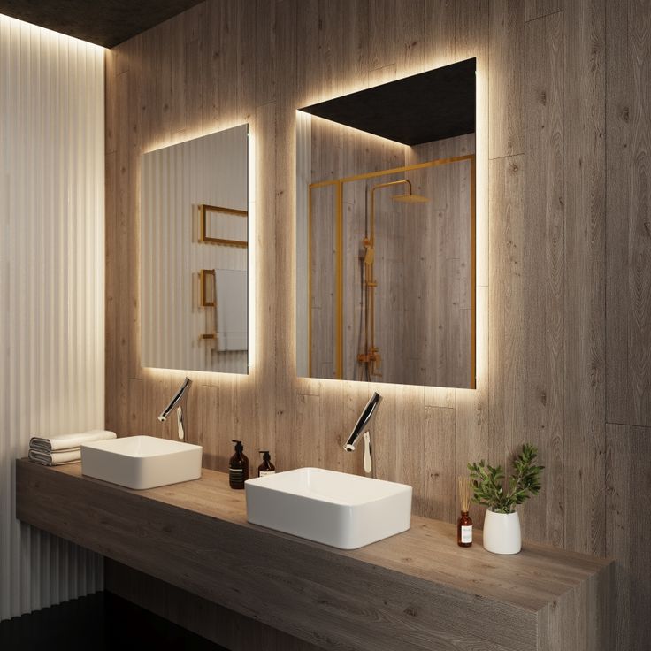 a bathroom with two sinks, mirrors and lights on the wall above them is shown