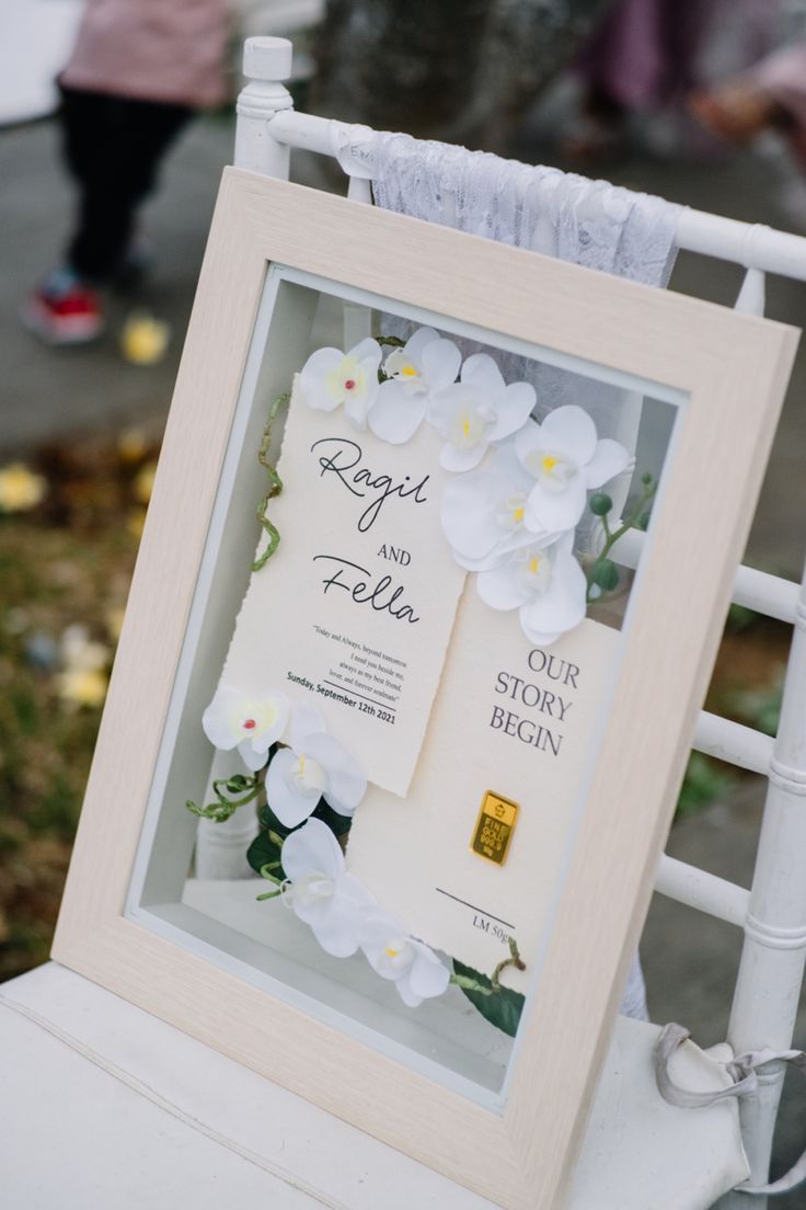 a white chair with flowers on it and a sign that says, roger and ellen our story begins