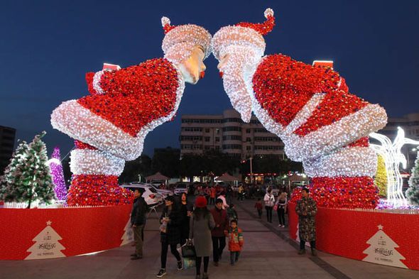 people are standing in front of christmas decorations at the entrance to a shopping area with lights and trees