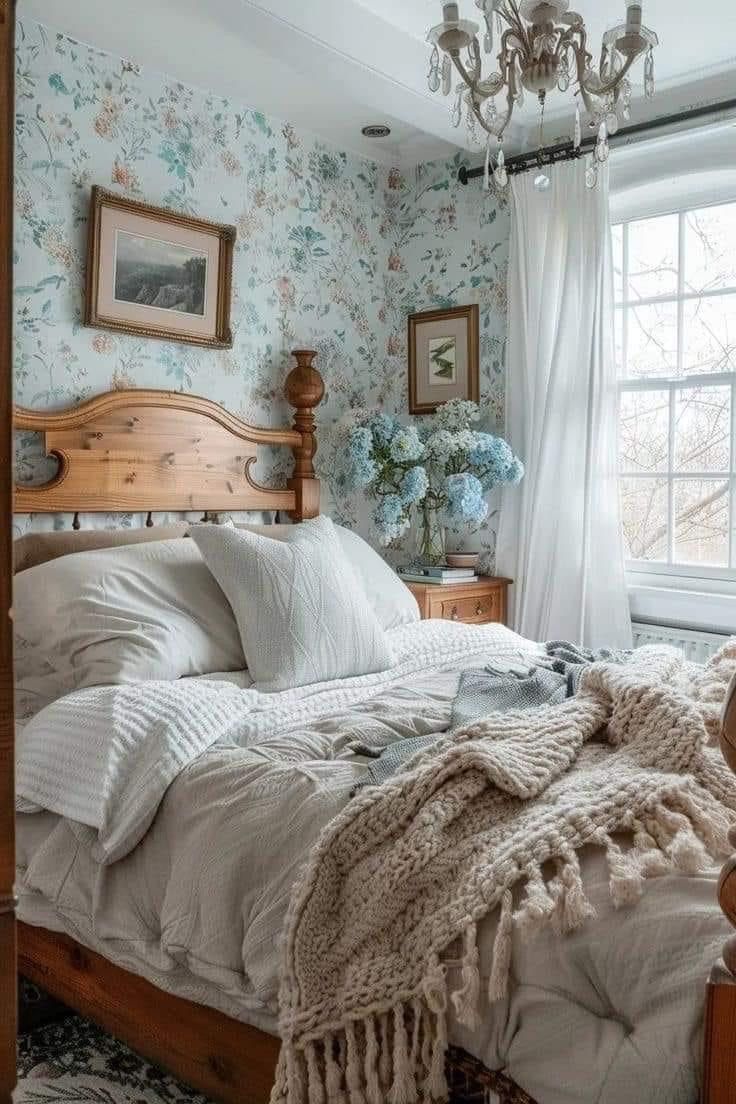 a bed sitting in a bedroom next to a window covered in white blankets and pillows