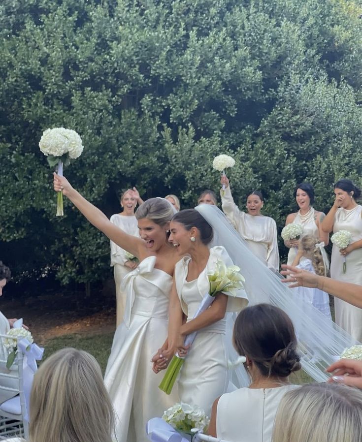 the bride and grooms are walking down the aisle with their arms in the air