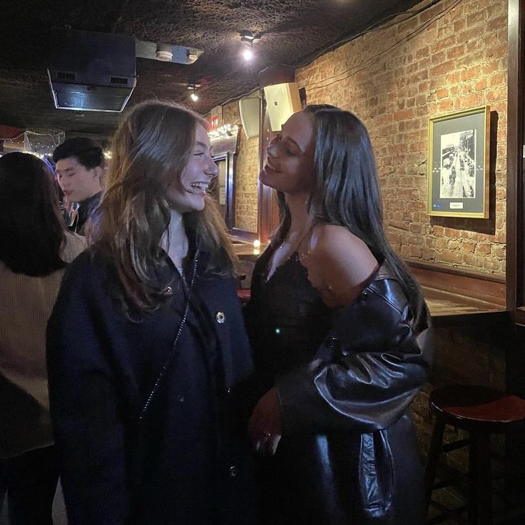 two women standing next to each other in a bar