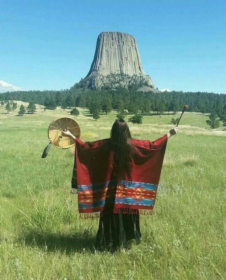 a woman standing in a field with a blanket on her shoulders