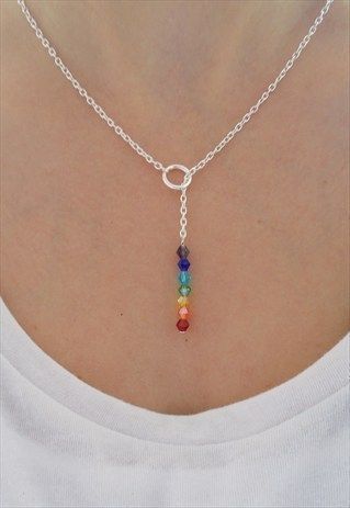 a woman wearing a white shirt with a rainbow necklace on her neck