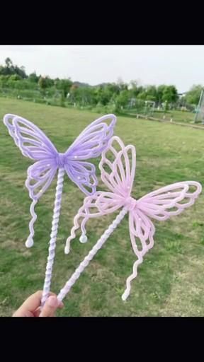 two purple and white plastic butterfly wands in the grass