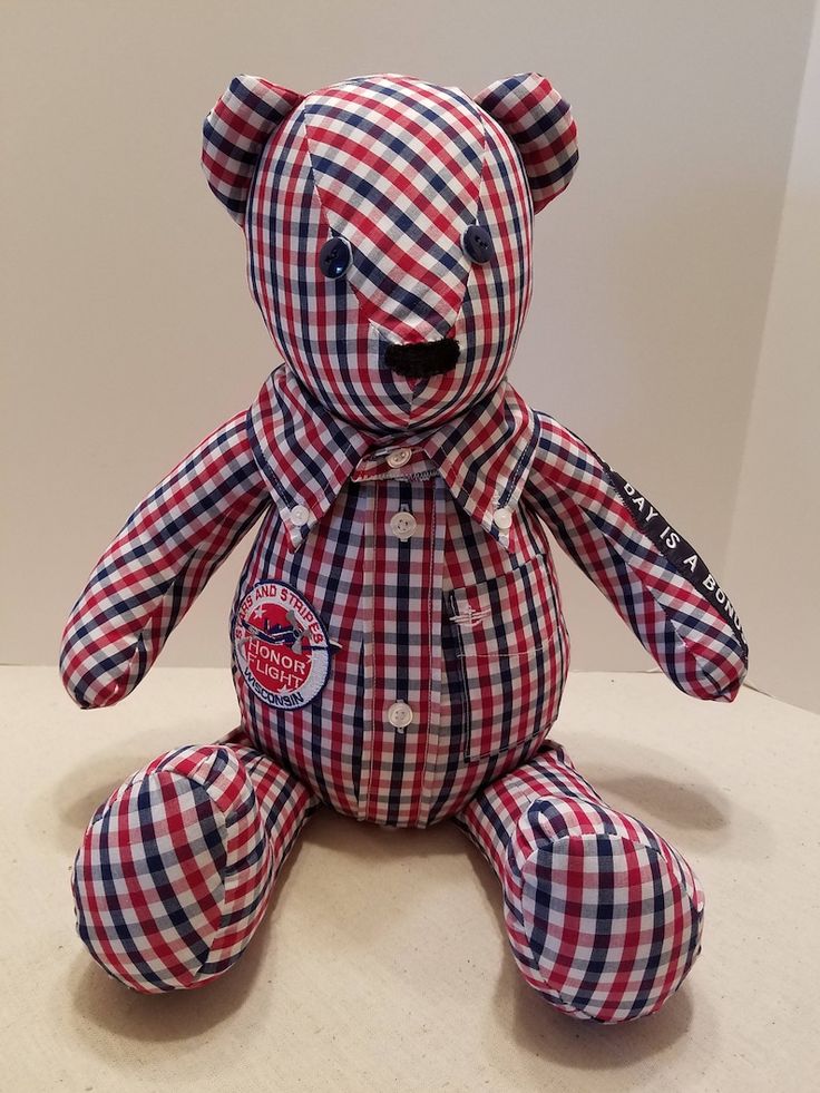 a red, white and blue teddy bear sitting on top of a table next to a wall