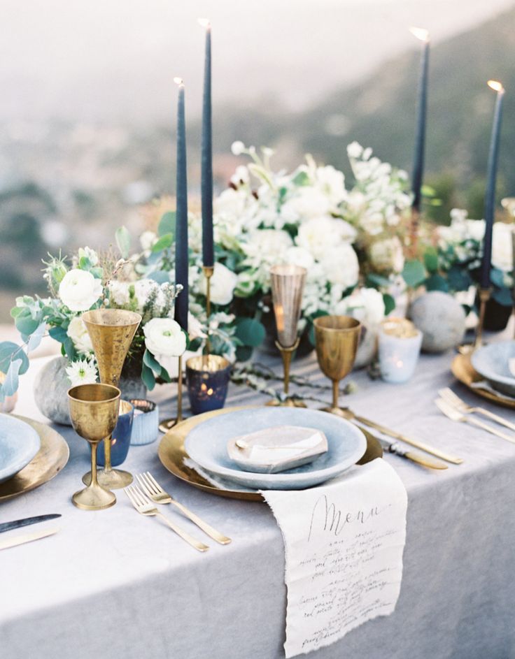 the table is set with candles, plates and silverware