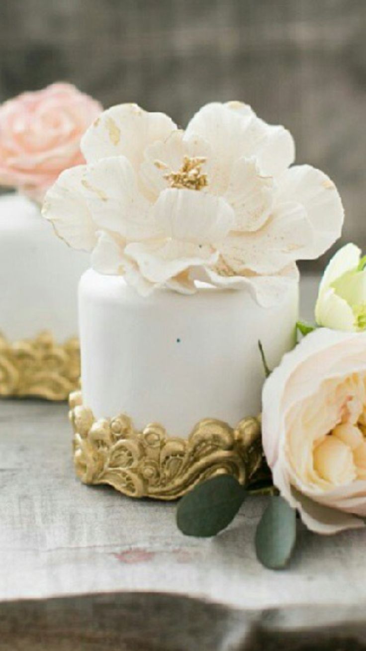 two small cakes with flowers on top of them sitting on a table next to each other