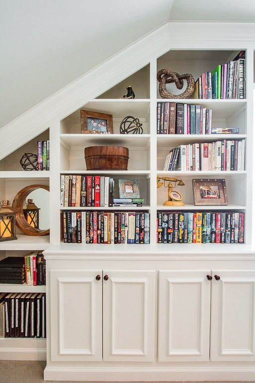 a bookshelf filled with lots of books under a slanted ceiling