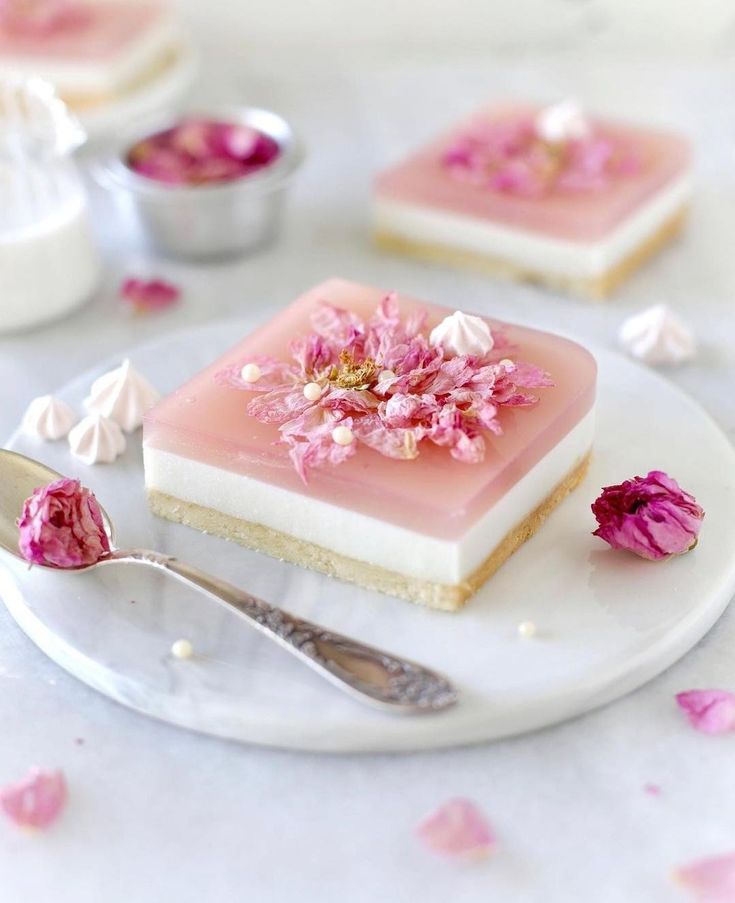 there is a piece of cake with pink flowers on it and two silver spoons