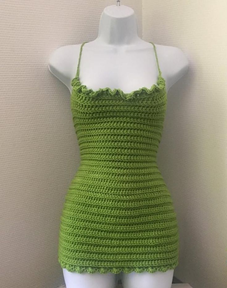 a mannequin wearing a green crochet dress on top of a table