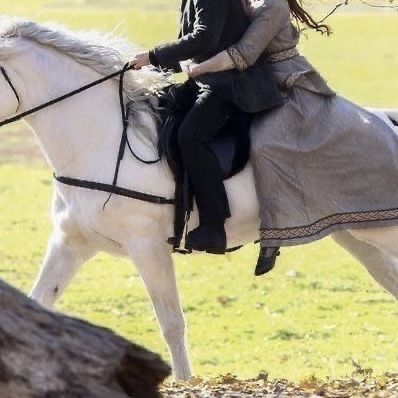 a woman riding on the back of a white horse