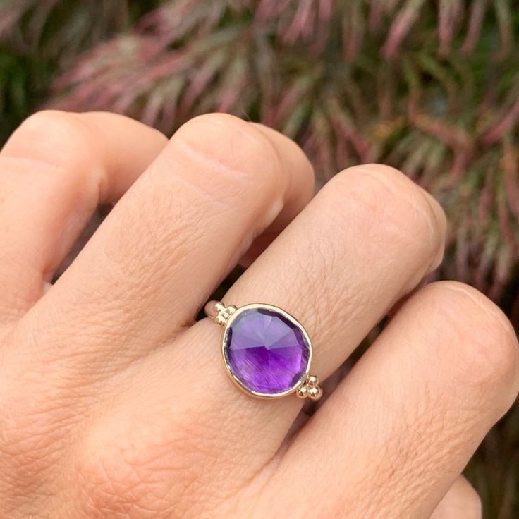 One of the most vibrant Amethysts we have come across, this rosecut gem is set in 14k yellow gold with gold accent beads, and a sterling silver freeform band. Approx stone size: 12mm x 10mm Approx ct weight: 3.2cts Mohs hardness: 8 This one of a kind piece is handmade with love in Emily's Hudson Valley studio. If you have questions about sizing, shipping or need help deciding on your perfect piece please reach out to us! Fine Jewelry Amethyst With Bezel Setting, Purple 14k Gold Jewelry With Accent Stones, Gold Amethyst Ring In 14k Gold, 14k Gold Amethyst Ring, Gold Faceted Amethyst Ring, Yellow Gold Amethyst Gemstone Ring, Faceted Amethyst Ring In Yellow Gold Fine Jewelry, Sterling Silver Ring With Gemstone Accents, Heirloom 14k Gold Amethyst Ring With Bezel Setting