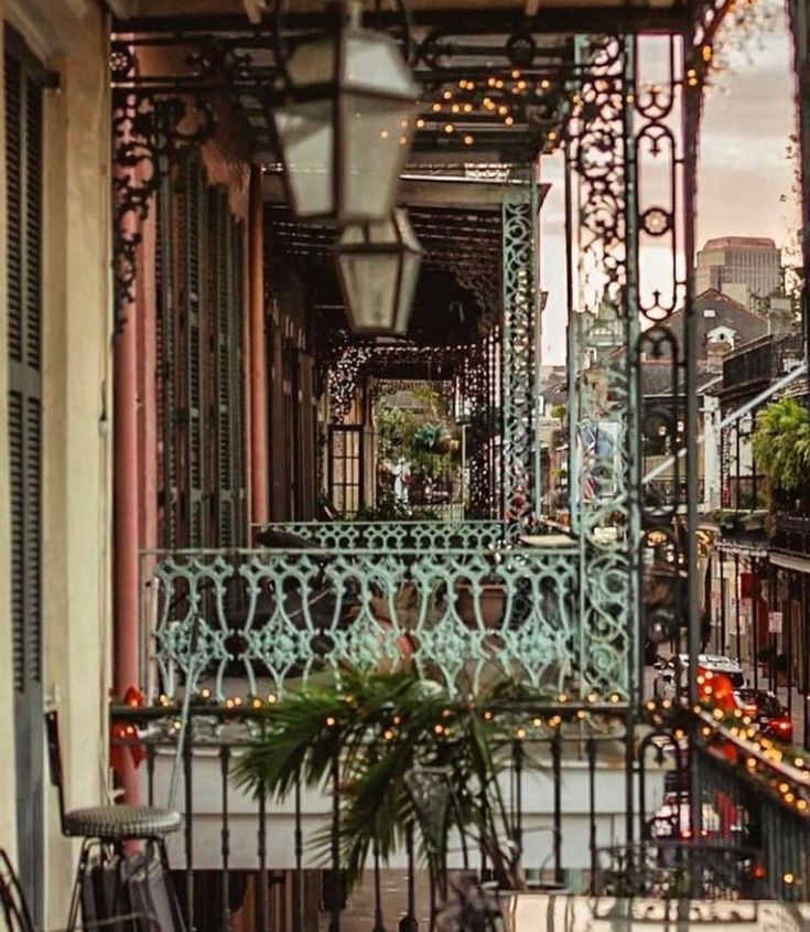 an outdoor balcony with lights and chairs on the outside, next to a potted plant