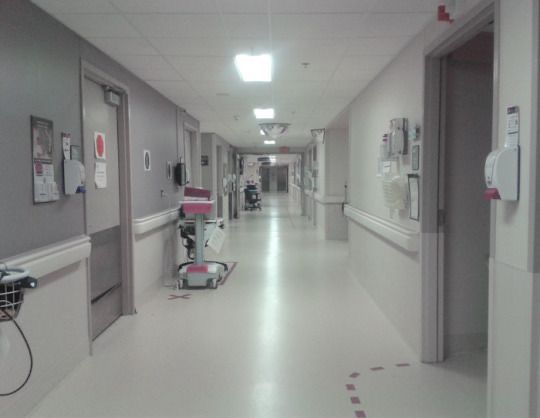 an empty hospital hallway with chairs and medical equipment