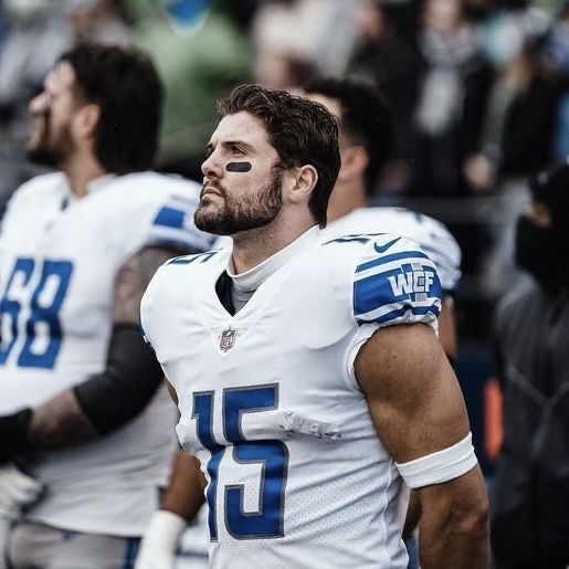 a football player standing on the sidelines with his hands in his pockets and looking off into the distance