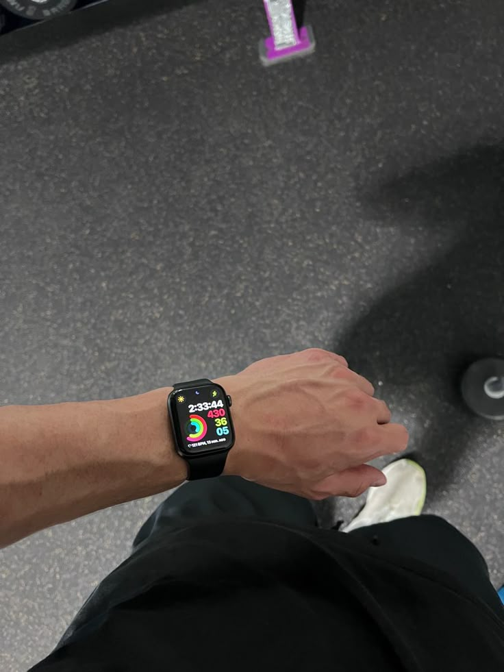 a person with a smart watch on their wrist standing in front of a skateboard