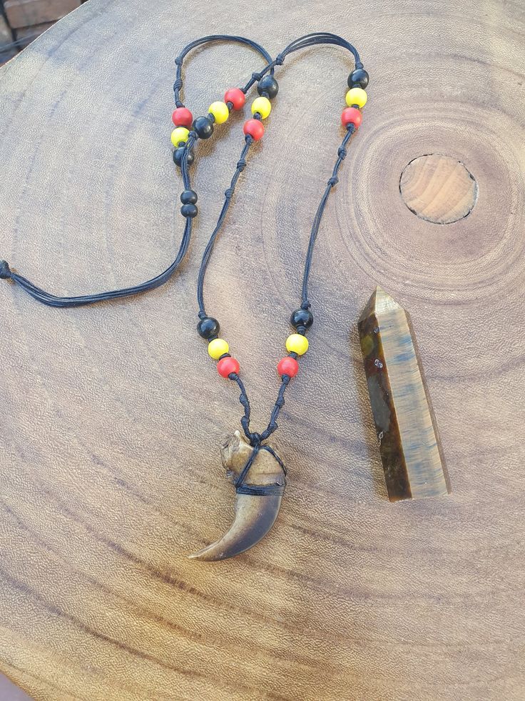 This necklace is made with a Resin Bear claw and timber beads. The string is 0.5mm black waxed string. The Tigers Eye Oblisque in video  is 51gm, 7.5cm x 2cm (Oblisque will vary for 2nd and 3rd items) Festival Amulet Style Jewelry With Wooden Beads, Wooden Beads Amulet Jewelry For Festival, Amulet Style Jewelry With Wooden Beads For Festival, Bear Claw Jewelry, Festival Amulet Jewelry With Wooden Beads, Unique Waxed Cord Festival Necklaces, Unique Waxed Cord Necklaces For Festivals, Adjustable Brown Necklace With Black Beads, Spiritual Hand-strung Jewelry In Waxed Cord