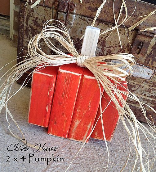 an orange pumpkin sitting on top of a floor next to a trunk with some branches hanging from it